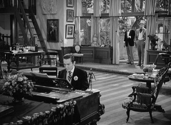 Movie still from “The Picture of Dorian Gray” (1945), directed by Albert Lewin – A man sitting at a piano in a living room; Wide shot, High angle