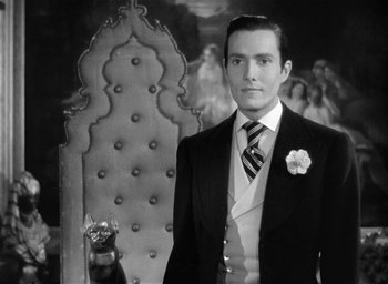 Movie still from “The Picture of Dorian Gray” (1945), directed by Albert Lewin – A man standing in front of an ornate chair; Medium shot, Low angle
