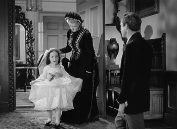 Movie still from “The Picture of Dorian Gray” (1945), directed by Albert Lewin – An old photo of two people and a little girl; Wide shot, Over the shoulder angle