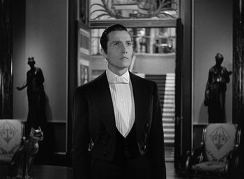 Movie still from “The Picture of Dorian Gray” (1945), directed by Albert Lewin – A man in a tuxedo standing in front of a staircase; Medium shot, Low angle
