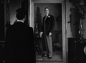 Movie still from “The Picture of Dorian Gray” (1945), directed by Albert Lewin – A black and white photo of a man standing in front of a mirror; Medium shot, Low angle