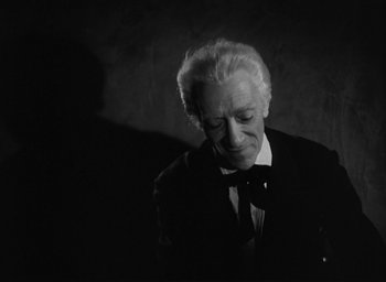 Movie still from “The Picture of Dorian Gray” (1945), directed by Albert Lewin – An older man in a suit and bow tie looking down; Close Up shot, High angle
