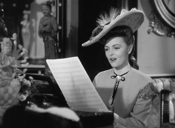 Movie still from “The Picture of Dorian Gray” (1945), directed by Albert Lewin – A woman wearing a hat is playing a sheet music; Close Up shot, Low angle