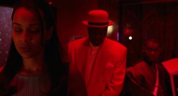Movie still from “The Players Club” (1998), directed by Ice Cube – A man wearing a red suit and a hat; Close Up shot, Over the shoulder angle