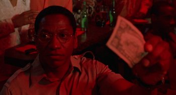 Movie still from “The Players Club” (1998), directed by Ice Cube – A man sitting at a table holding a newspaper; Close Up shot, Low angle