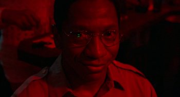 Movie still from “The Players Club” (1998), directed by Ice Cube – A person wearing glasses in a dark room; Close Up shot, Low angle