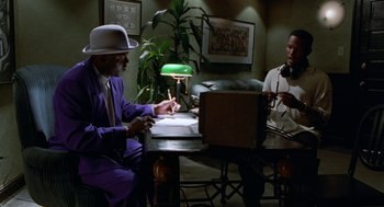 Movie still from “The Players Club” (1998), directed by Ice Cube – Two men sitting at a table in front of a laptop; Medium shot, Low angle