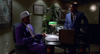 Movie still from “The Players Club” (1998), directed by Ice Cube – Two men in suits sitting at a table; Medium shot, Low angle