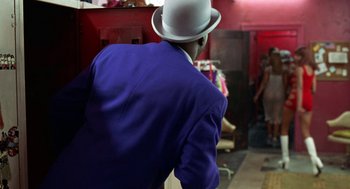 Movie still from “The Players Club” (1998), directed by Ice Cube – A man wearing a blue suit and a white hat; Medium shot, Over the shoulder angle