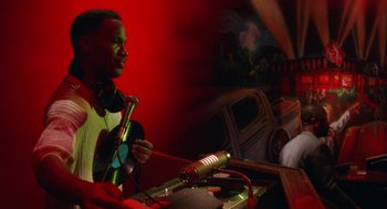 Movie still from “The Players Club” (1998), directed by Ice Cube – A man holding a microphone in front of a microphone stand; Medium shot, Low angle