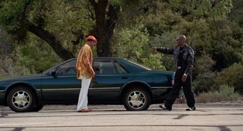 Movie still from “The Players Club” (1998), directed by Ice Cube – Two men are walking down the street in front of a car; Wide shot, High angle