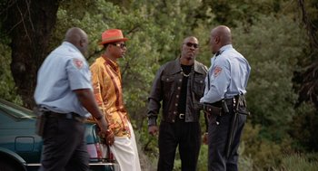 Movie still from “The Players Club” (1998), directed by Ice Cube – A group of men standing next to each other near a tree; Medium shot, Over the shoulder angle