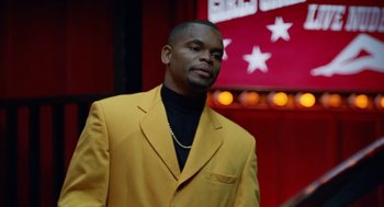Movie still from “The Players Club” (1998), directed by Ice Cube – A man in a yellow suit standing in front of a red wall; Close Up shot, Low angle