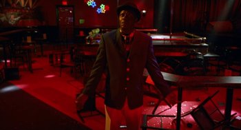 Movie still from “The Players Club” (1998), directed by Ice Cube – A man wearing a suit and hat standing in a room; Medium shot, Low angle