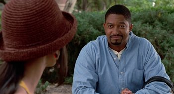 Movie still from “The Players Club” (1998), directed by Ice Cube – A man sitting in front of a woman in front of bushes; Close Up shot, Over the shoulder angle