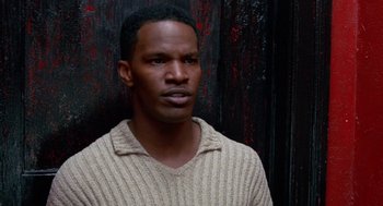 Movie still from “The Players Club” (1998), directed by Ice Cube – A black man in a white sweater looking at the camera; Close Up shot, High angle