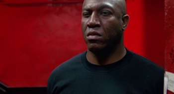 Movie still from “The Players Club” (1998), directed by Ice Cube – A bald man with a black shirt is looking to his left; Close Up shot, Low angle