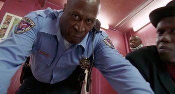 Movie still from “The Players Club” (1998), directed by Ice Cube – A man in a police uniform holding a microphone; Close Up shot, Low angle