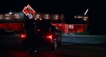 Movie still from “The Players Club” (1998), directed by Ice Cube – A person standing next to a car on a street at night; Wide shot, Low angle