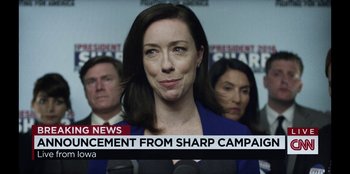 Movie still from “House of Cards” (2013), created by Beau Willimon – A woman in a blue jacket is talking to the press; Close Up shot, Low angle