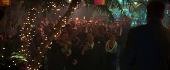 Movie still from “The Pledge” (2001), directed by Sean Penn – A group of people standing in front of a palm tree at night; Wide shot, High angle