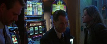 Movie still from “The Pledge” (2001), directed by Sean Penn – A man in a suit and tie sitting in front of slot machines; Close Up shot, Over the shoulder angle