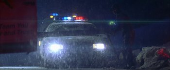 Movie still from “The Pledge” (2001), directed by Sean Penn – A police car with its lights turned on at night; Wide shot, Low angle