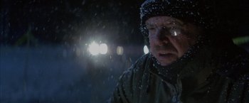 Movie still from “The Pledge” (2001), directed by Sean Penn – A man with glasses is standing in the snow; Close Up shot, Over the shoulder angle