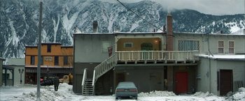 Movie still from “The Pledge” (2001), directed by Sean Penn – A car parked in front of a house in the snow; Extreme Wide shot, High angle
