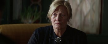 Movie still from “The Pledge” (2001), directed by Sean Penn – An older woman wearing a black shirt and a necklace; Close Up shot, Over the shoulder angle