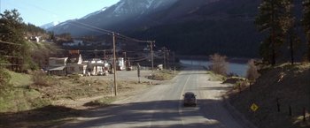 Movie still from “The Pledge” (2001), directed by Sean Penn – A car driving down a road with power lines overhead; Extreme Wide shot, High angle