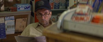 Movie still from “The Pledge” (2001), directed by Sean Penn – A man wearing glasses and a hat is looking at the camera; Close Up shot, Over the shoulder angle