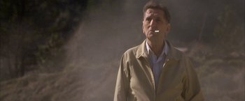 Movie still from “The Pledge” (2001), directed by Sean Penn – A man in a tan jacket is smoking a cigarette; Medium shot, Low angle