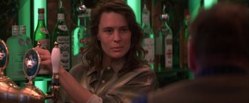 Movie still from “The Pledge” (2001), directed by Sean Penn – A woman sitting at a bar in front of bottles of alcohol; Close Up shot, Over the shoulder angle