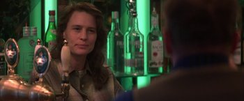 Movie still from “The Pledge” (2001), directed by Sean Penn – A woman sitting in front of a wall of alcohol bottles; Close Up shot, Over the shoulder angle