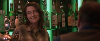 Movie still from “The Pledge” (2001), directed by Sean Penn – A woman smiling in front of a wall full of bottles; Close Up shot, Over the shoulder angle