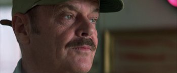Movie still from “The Pledge” (2001), directed by Sean Penn – A man with a mustache wearing a baseball cap; Close Up shot, Over the shoulder angle