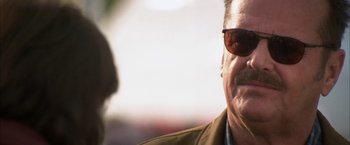 Movie still from “The Pledge” (2001), directed by Sean Penn – An older man wearing a jacket and sunglasses; Close Up shot, Over the shoulder angle