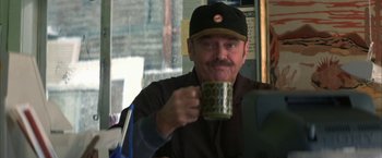 Movie still from “The Pledge” (2001), directed by Sean Penn – A man holding a coffee mug while sitting at a table; Close Up shot, Over the shoulder angle