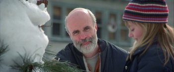 Movie still from “The Pledge” (2001), directed by Sean Penn – A man with a beard is sitting in front of a tree; Close Up shot, Low angle
