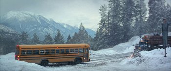 Movie still from “The Pledge” (2001), directed by Sean Penn – A school bus driving down a snow covered road; Extreme Wide shot, High angle