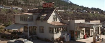 Movie still from “The Pledge” (2001), directed by Sean Penn – An old gas station is shown in a mountainous area; Extreme Wide shot, High angle
