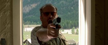Movie still from “The Pledge” (2001), directed by Sean Penn – A man with sunglasses is holding a gun; Close Up shot, Low angle