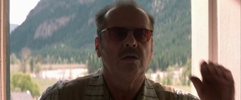 Movie still from “The Pledge” (2001), directed by Sean Penn – An older man wearing sunglasses in front of trees; Close Up shot, Low angle