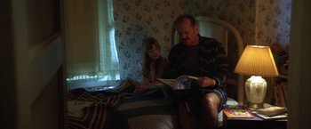 Movie still from “The Pledge” (2001), directed by Sean Penn – A man and a little girl sitting on a bed reading; Medium shot, Low angle