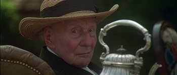 Movie still from “The Portrait of a Lady” (1996), directed by Jane Campion – An old man wearing a straw hat looking at a silver tea pot; Close Up shot, Low angle