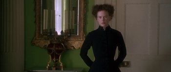 Movie still from “The Portrait of a Lady” (1996), directed by Jane Campion – A woman standing in front of a mirror in a room; Medium shot, Low angle