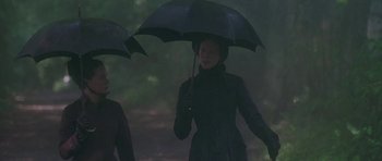 Movie still from “The Portrait of a Lady” (1996), directed by Jane Campion – A woman holding an umbrella while standing in the rain; Medium shot, Low angle