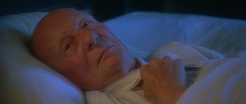 Movie still from “The Portrait of a Lady” (1996), directed by Jane Campion – An older man laying in bed with his hand on his chest; Close Up shot, High angle
