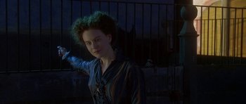 Movie still from “The Portrait of a Lady” (1996), directed by Jane Campion – A young woman with a green curly hairdo standing in front of a fence; Medium shot, Over the shoulder angle